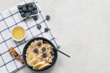 Lezzetli yulaf ezmeli kase, beyaz grunge arka planda muz ve yaban mersini parçaları.