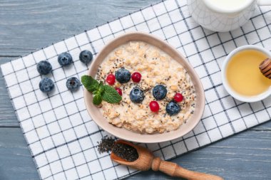 Peçeteli kompozisyon, lezzetli yulaf ezmesi ve gri ahşap arka planda böğürtlen.