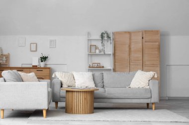 Gri kanepeleri ve masası olan aydınlık oturma odasının içinde.