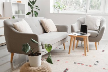 Sehpanın üzerinde kanepe, koltuk ve dizüstü bilgisayarı olan bir oturma odası.