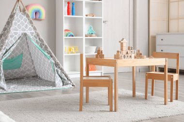 Oyun çadırı, masa ve oyuncakları olan çocuk odasının içinde.