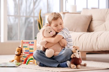 Evde yerde oyuncak tavşanı kucaklayan sevimli küçük çocuk.