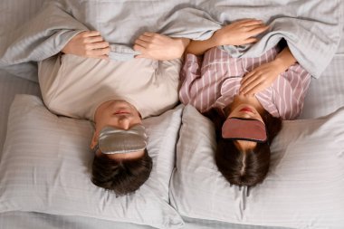 Yatakta maskeli genç bir çift var.