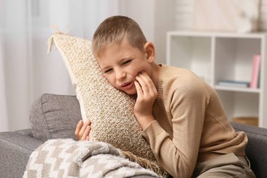Evde diş ağrısı çeken küçük bir çocuk.