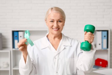 Klinikte donuk kurdeleli ve dambılı olan olgun bir kadın doktor. Rahim Sağlığı Bilinci Ayı