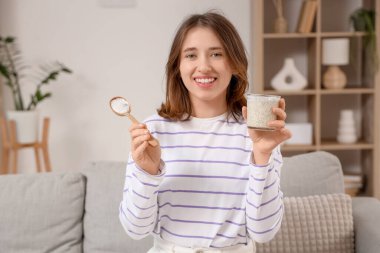 Chia tohumu yoğurtlu genç kadın evdeki kanepede oturuyor.
