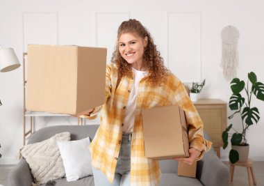 Evde paket kutuları tutan genç bir kadın.