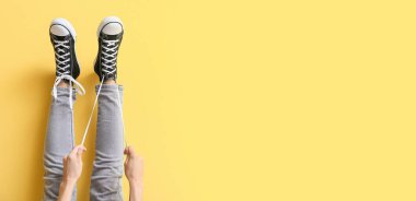 Sarı zemin üzerinde beyaz bağcıklar bağlayan çizmeli kadın ve metin için boşluk