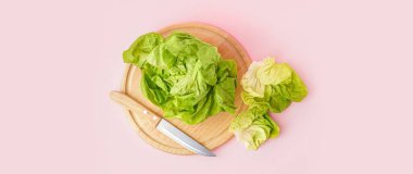 Cutting board, fresh Boston lettuce and knife on pink background, top view clipart