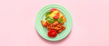 Domatesli fırında makarna ve pembe arka planda peynir.