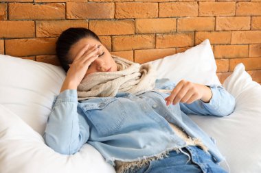 Yatak odasında termometresi olan hasta genç bir kadın.