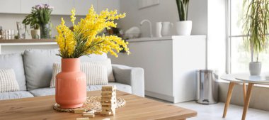 Mimoza çiçekli vazo ve stüdyo dairesindeki masada oyun için tahta bloklar.