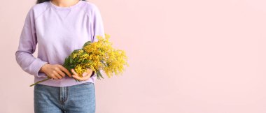 Pembe arka planda güzel mimoza dalları ve metin için yeri olan bir kadın.