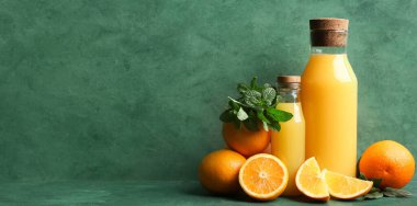 Yeşil arka planda lezzetli portakal suyu ve nane yaprakları ve metin için yer var.