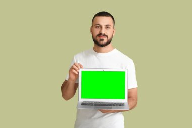 Yeşil arka planda boş ekranlı dizüstü bilgisayarı olan genç bir adam. Tasarım için model