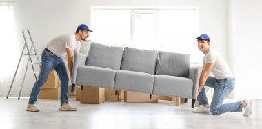 Loaders carrying sofa in room