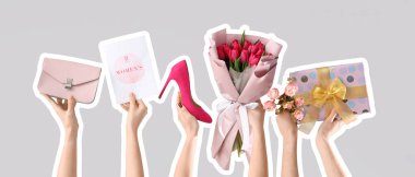 Çiçekli kadın elleri, hediye kutusu, kart, ayakkabı ve el çantası gri arka planda. Uluslararası Kadınlar Günü