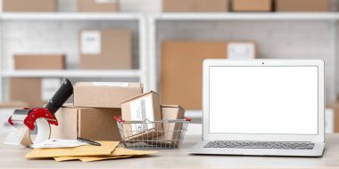 Posta deposundaki masada paket kutularıyla ve bant dağıtıcıyla dizüstü bilgisayar.