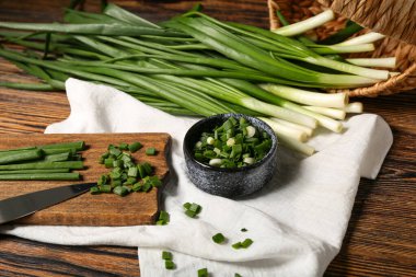Ahşap zemin üzerinde taze yeşil soğan olan yemek ve kase.