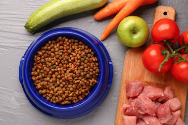 İçinde kuru hayvan mamaları, çiğ et ve ahşap arka planda doğal ürünler olan bir kase.