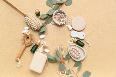 Kozmetik ürünlerden, banyo malzemelerinden ve renk arkaplanındaki okaliptüs dallarından yapılmış çerçeve