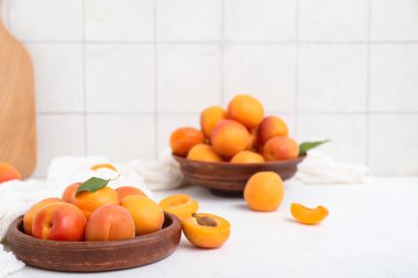 Beyaz masada taze kayısılar ve tabaklar.