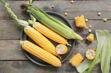 Gri ahşap masada taze mısır koçanı tabağı.