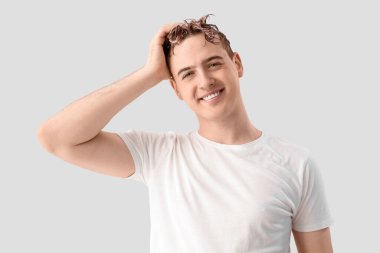 Genç adam arka planda saç yıkıyor.