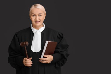 Siyah arka planda kitap ve tokmakla olgun kadın yargıç.