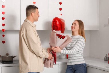 Evde sevgililer gününü kutlayan kalp şeklinde balonları ve gül buketiyle güzel genç bir çift.