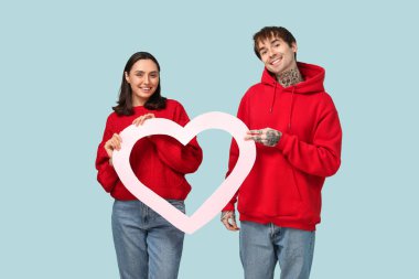 Mavi arka planda kalp şeklinde bir çerçeveye sahip genç bir çift. Sevgililer Günü kutlaması