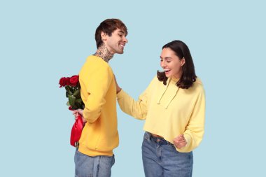 Young man greeting his beloved girlfriend with Valentine's day on blue background