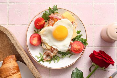 Lezzetli kızarmış yumurta, tost, pastırma, domates ve arkaplanda gül çiçeği.