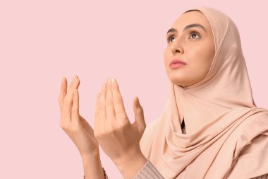Genç Müslüman kadın pembe arka planda dua ediyor