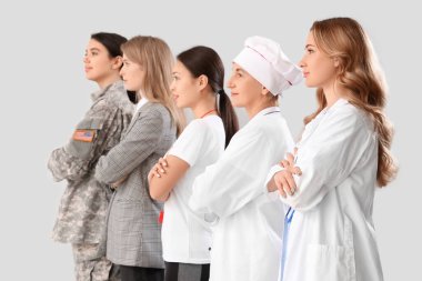 Gri arka planda çapraz kollu farklı meslekten kadınlar.