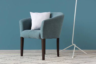 Mavi duvarın yanındaki koltuğu ve yastığı olan oturma odasının içinde.