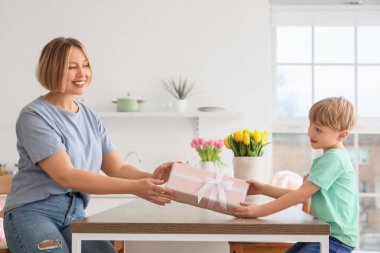 Mutfaktaki küçük oğlundan hediye alan mutlu bir anne. Uluslararası Kadınlar Günü