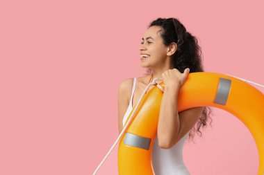 Pembe arka planda halka şamandırası olan güzel, mutlu, Afro-Amerikan kadın cankurtaran.