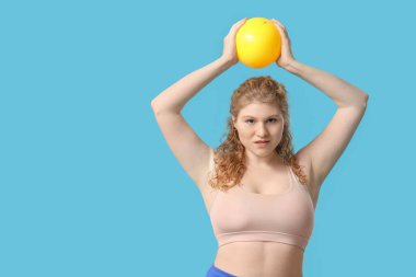 Mavi arka planda topları olan genç bir kadın.