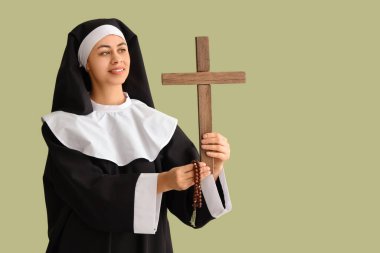Yeşil arka planda haçlı ve boncuklu genç rahibe.
