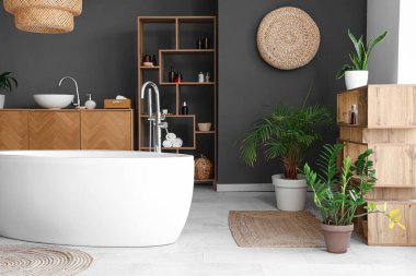 Küvetli, ahşap mobilyalı ve çiçekli modern banyo.