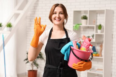 Elinde kova dolusu temizlik malzemesi olan genç bir kadın evde iyi görünüyor.