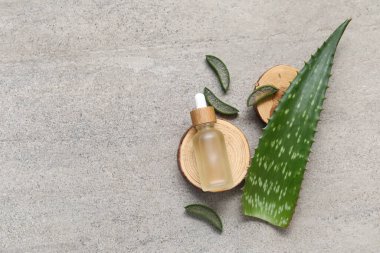 Ahşap stantlar ve gri arka planda gerekli aloe vera yağı şişesi