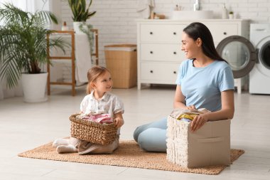 Genç bir kadın ve iki sepet dolusu çamaşırları olan küçük kızı.