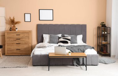 Rahat yataklı şık bir oda, dizüstü bilgisayarlı bank, çekmeceler ve raf ünitesi.