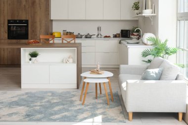 Modern bir stüdyo daire mutfak tezgahı, şık bir kanepe ve pencere kenarındaki masa.