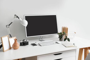 Modern bilgisayar ve ışık duvarının yanında fotoğraf makinesi olan şık bir iş yeri.