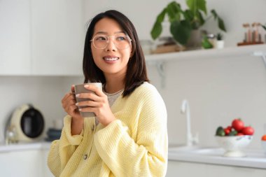 Mutfakta bir fincan lezzetli çayla güzel bir Asyalı kadın.