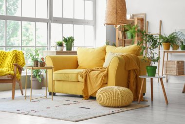 Sarı kanepeli ve çiçekli modern oturma odasının içi.