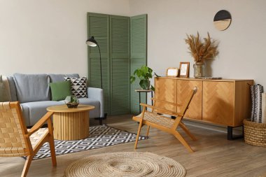 Gri kanepesi, koltuğu ve sehpası olan modern oturma odasının içinde.